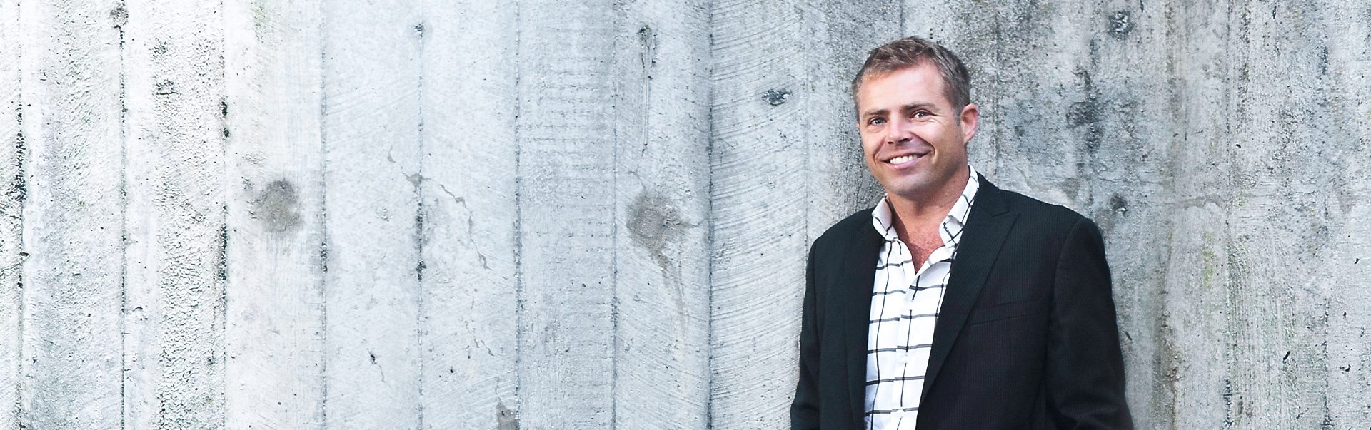 Andrew Orr, lawyer at AJO Legal, standing against a concrete wall